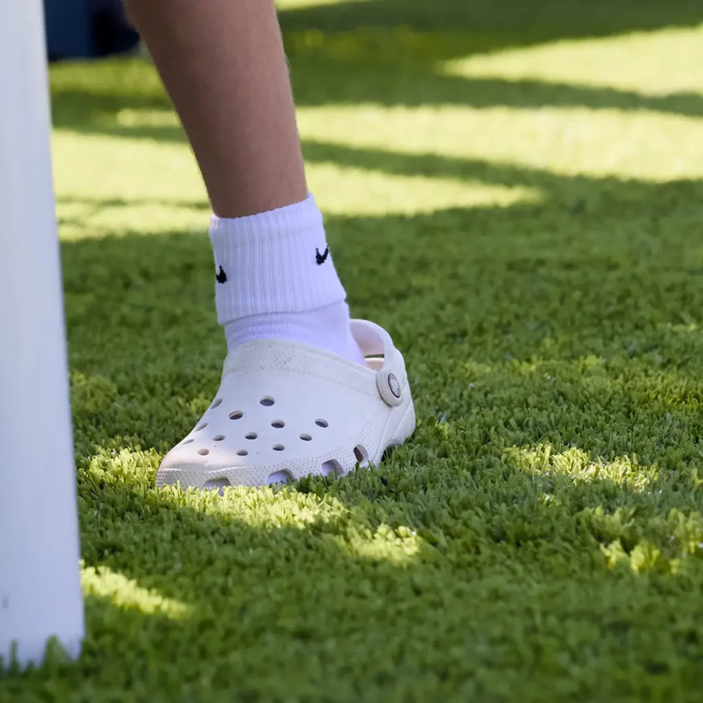 White Crocs with Nike socks on vibrant green Playground Grass Ultra artificial turf at Hoagland Park playground.