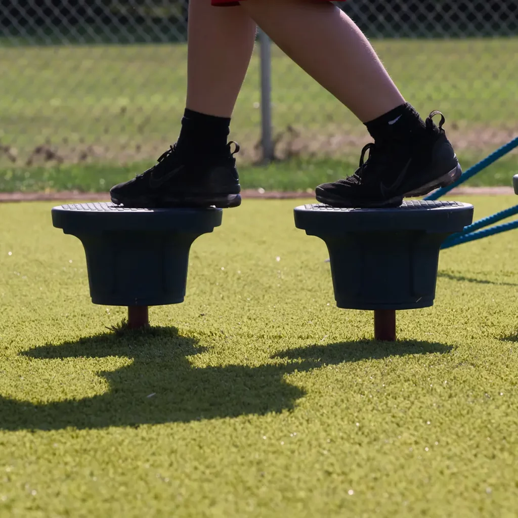 Child standing on playground stepping stone stumps over Playground Grass Ultra artificial turf at Hoagland Park.
