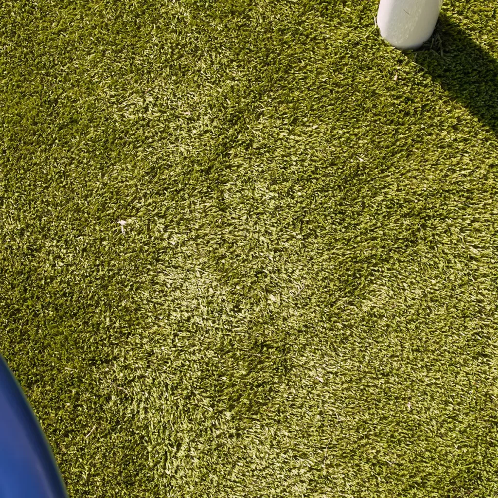 Close-up of Playground Grass Ultra artificial turf installation at Hoagland Park municipal playground with white post anchor visible.