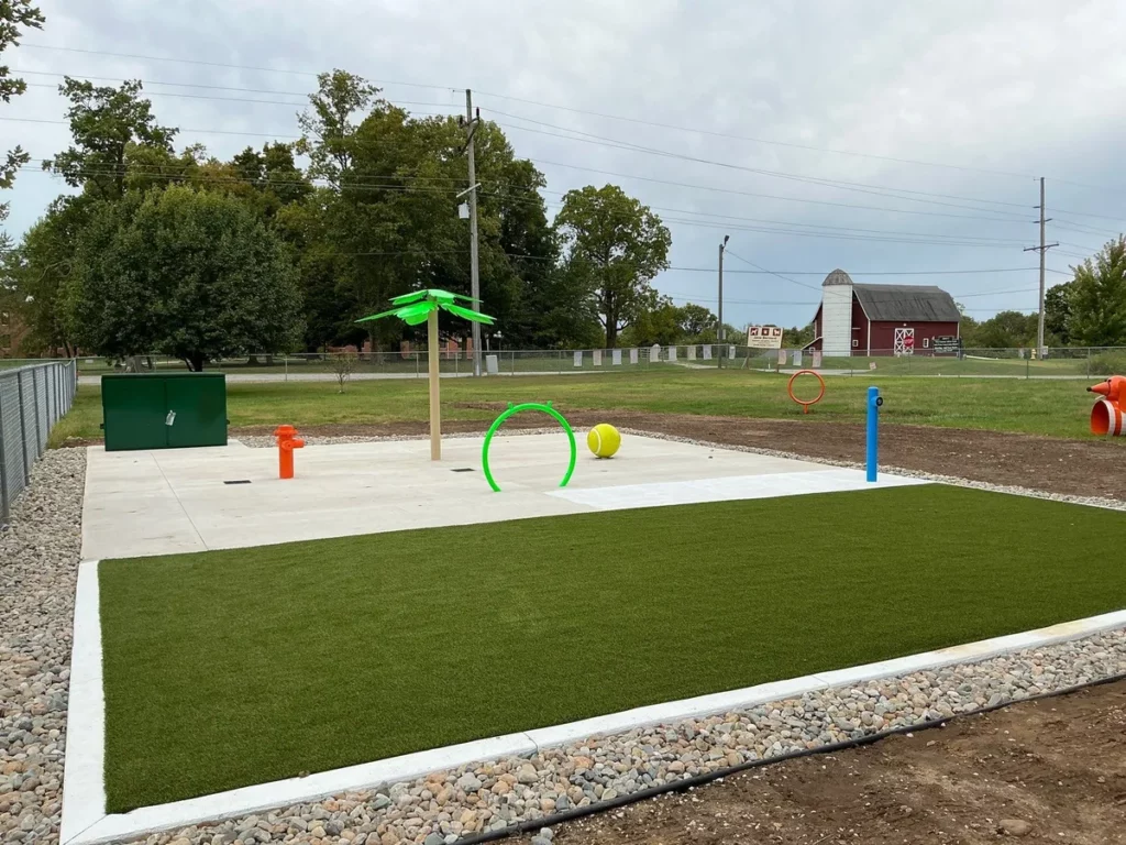 K9Grass Elite artificial turf pet yard with splash pad features, 465 sq ft, adjacent to red barn in La Porte