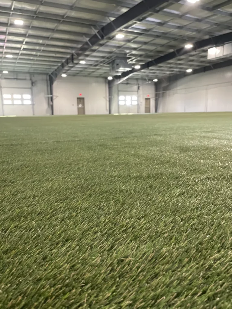 Indoor K9Grass artificial turf installation covering large pet facility with steel beam ceiling and LED lighting