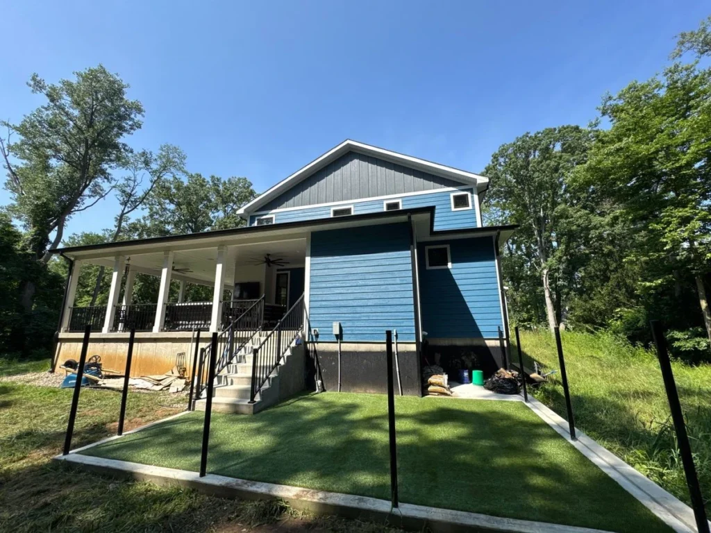 K9Grass artificial turf installed in fenced residential backyard beside blue two-story home with covered porch, Mishawaka