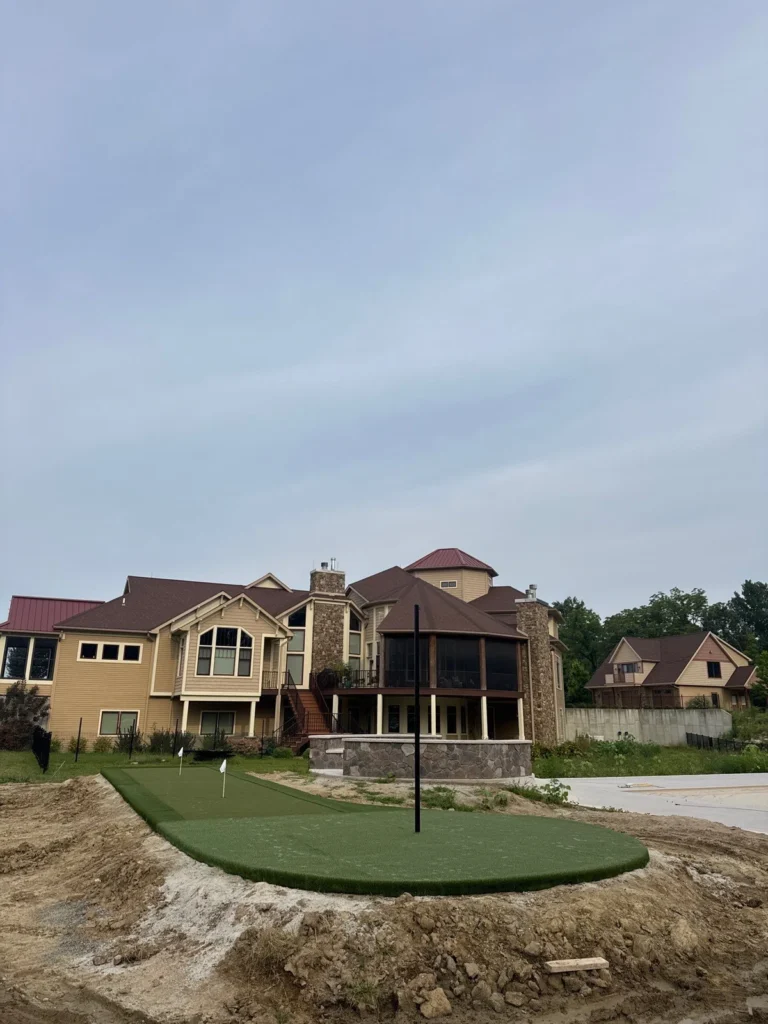 GolfGreens artificial putting green with flag installed in backyard of large luxury home, Columbia City, mid-construction landscaping