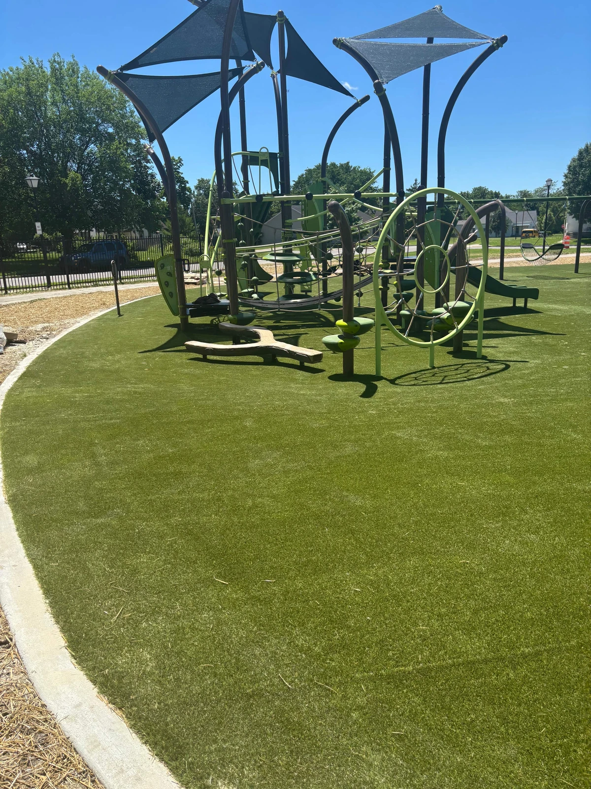 ForeverLawn Playground Grass Ultra installed at Hanna Homestead Park beneath modern nature-themed play structures and shade sails.